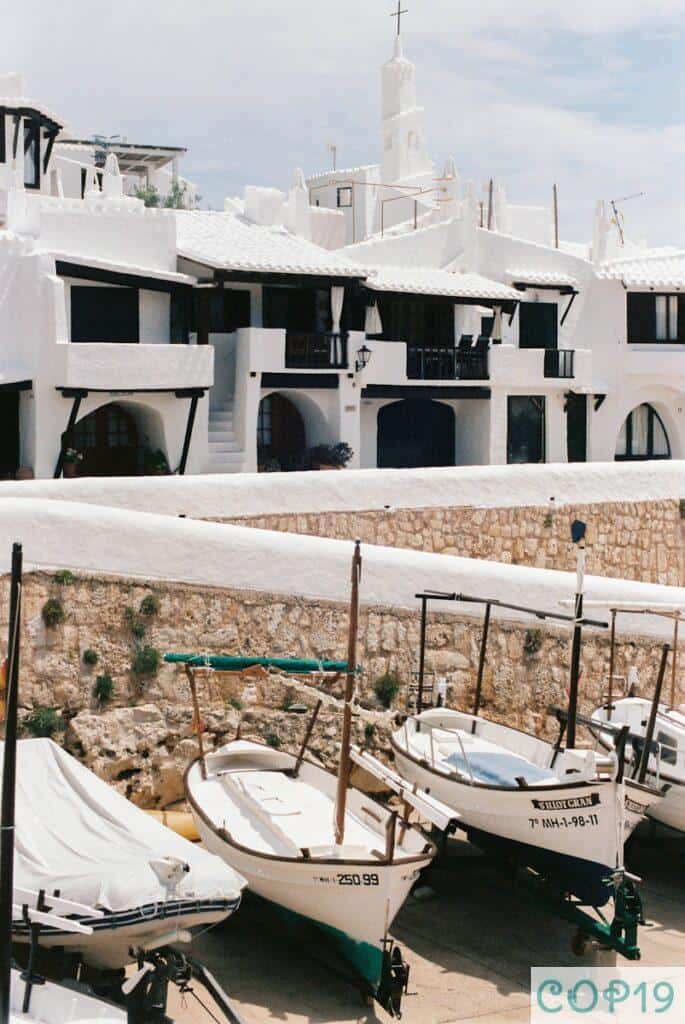 white and blue boat on white sand beach during daytime