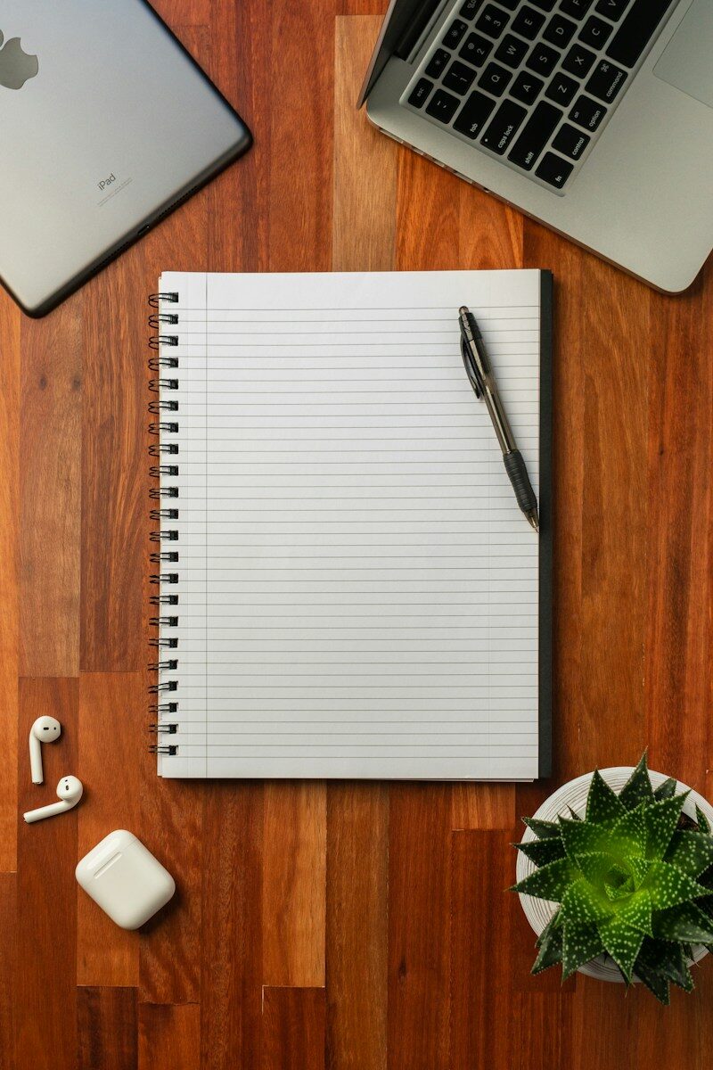 Escritorio de redacción con cuaderno, bolígrafo y portátil